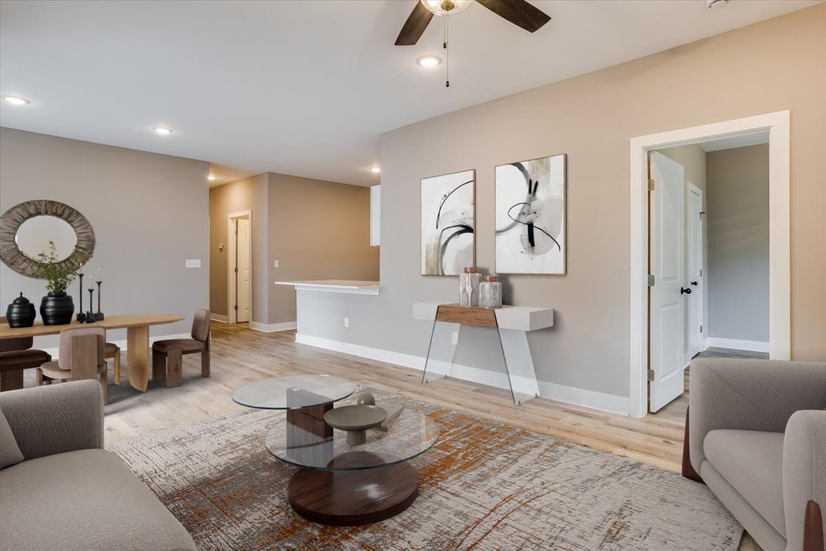 A living room with a ceiling fan , two chairs , a table and a rug.