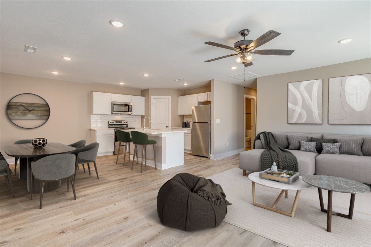 A living room with a couch , table , chairs and a ceiling fan.