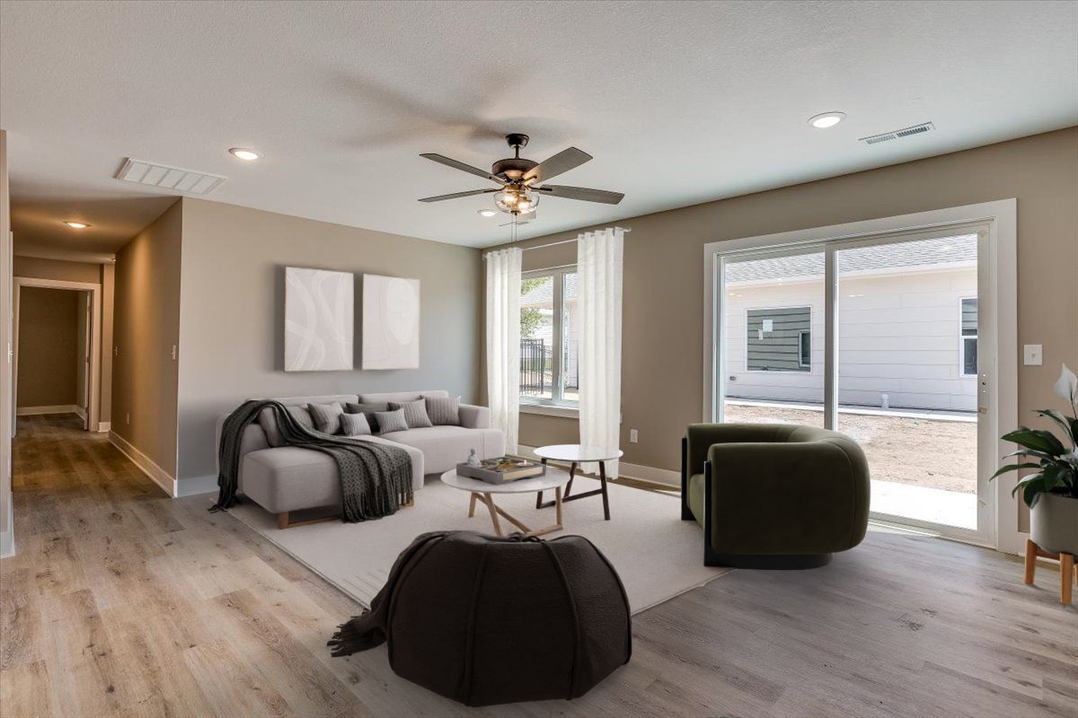 A living room with a couch , chairs , and a ceiling fan.