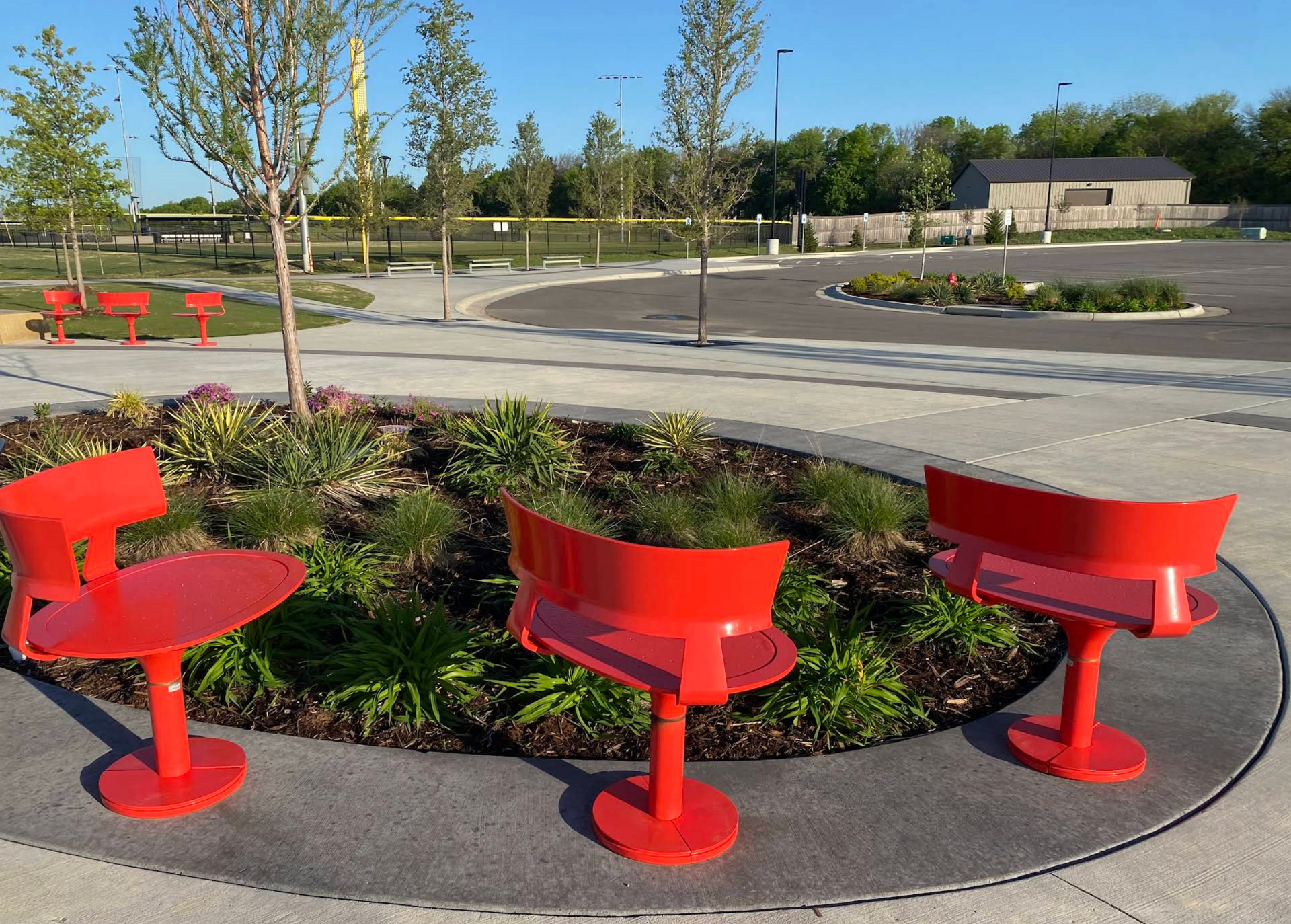 Three red chairs are sitting in a circle in a park