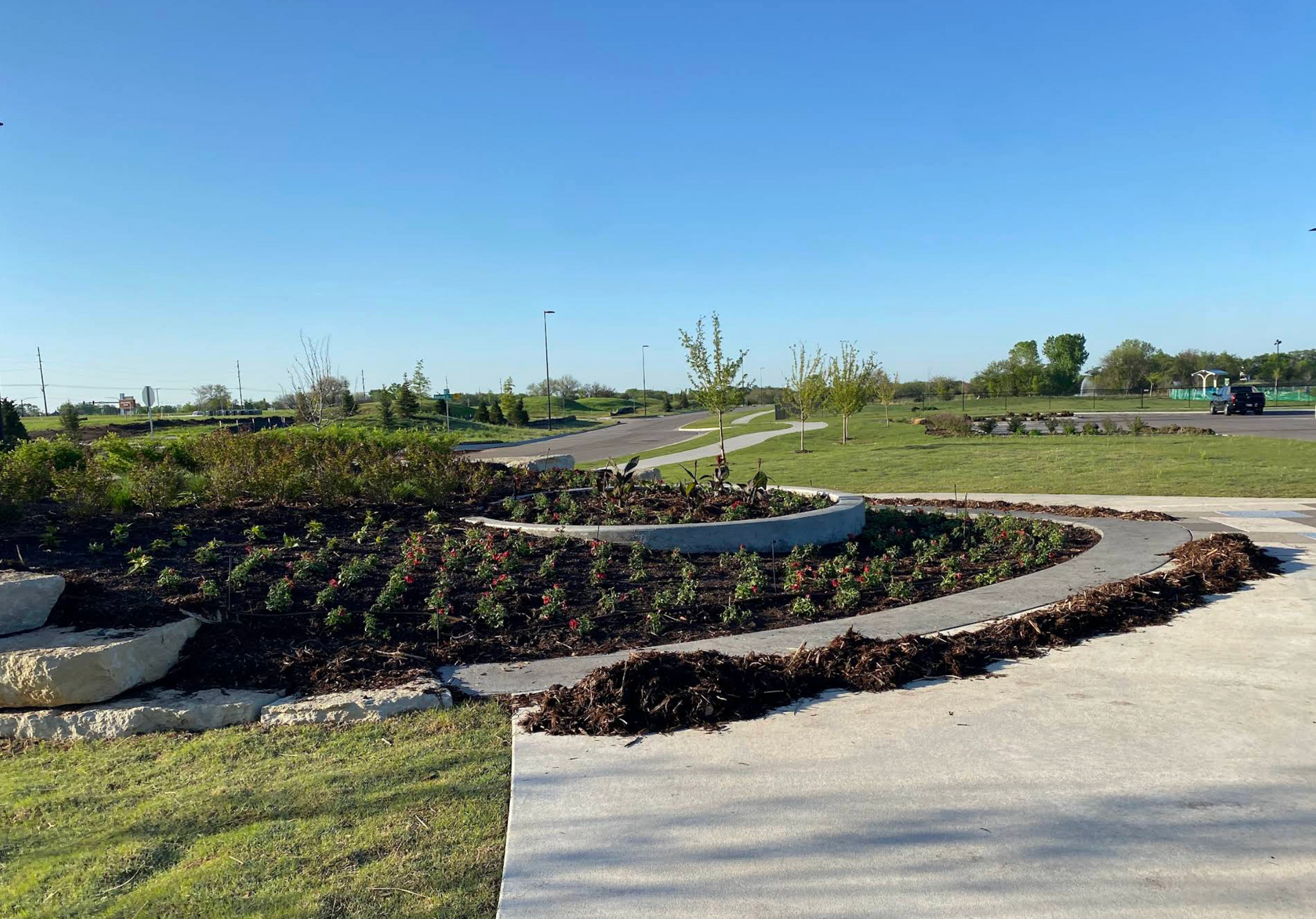 A concrete walkway surrounded by grass and trees in a park