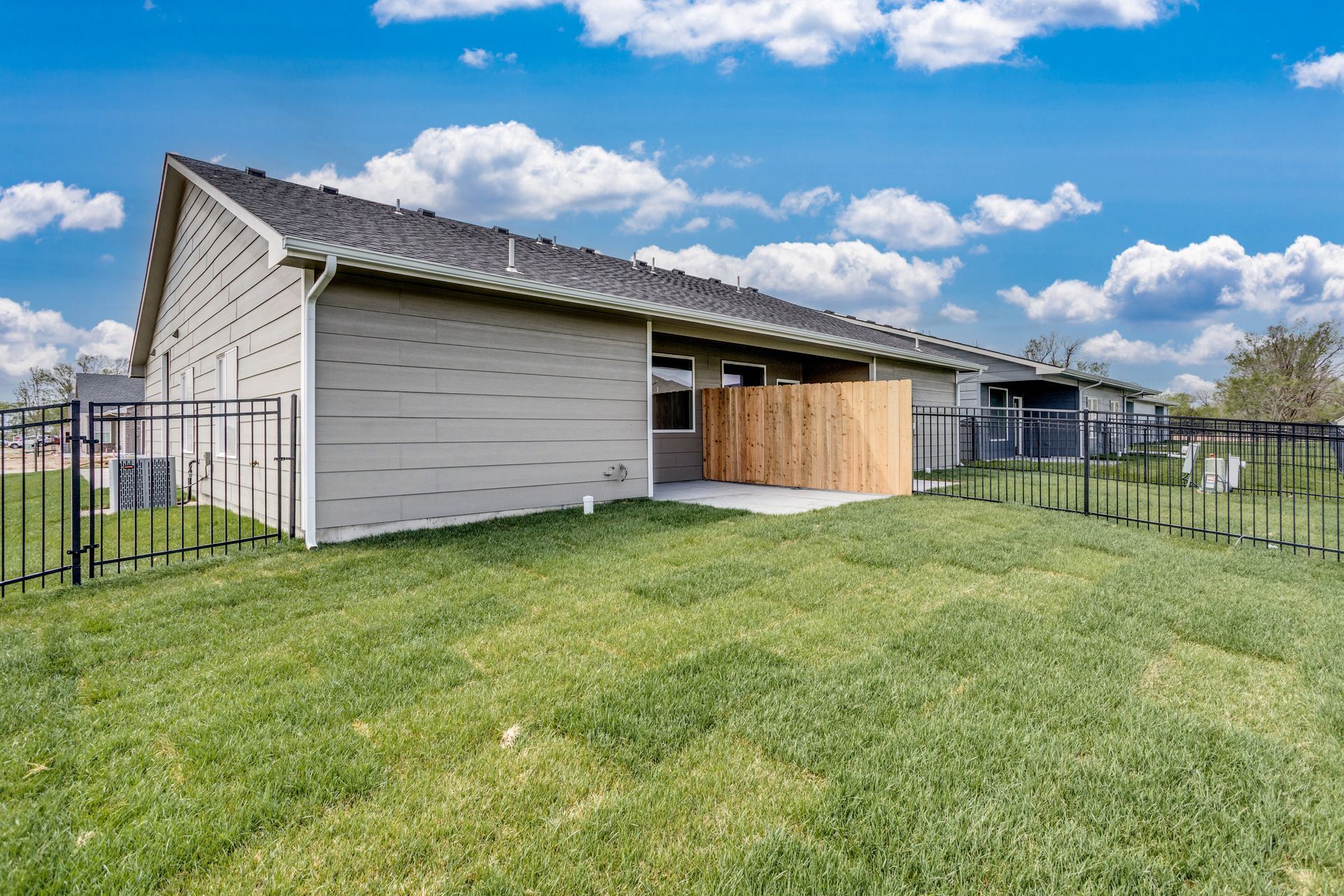 A house with a fence around it and a large lawn in front of it.