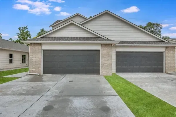 A house with two garage doors and a concrete driveway