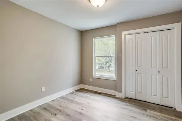 An empty bedroom with a window and a closet.