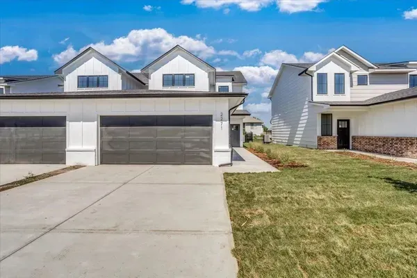 A white house with two garages is for sale in a residential area.