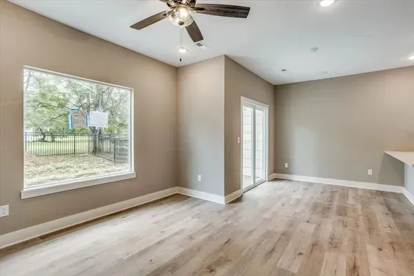 An empty living room with hardwood floors and a ceiling fan.
