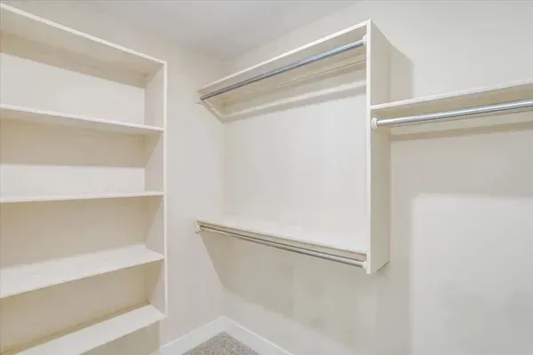 A walk in closet with lots of shelves and clothes racks.