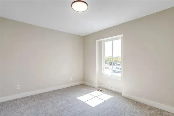 An empty bedroom with a window and a light on the ceiling.