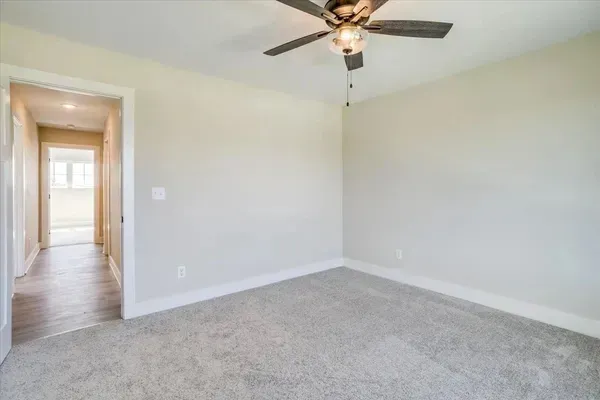 An empty bedroom with a ceiling fan hanging from the ceiling.