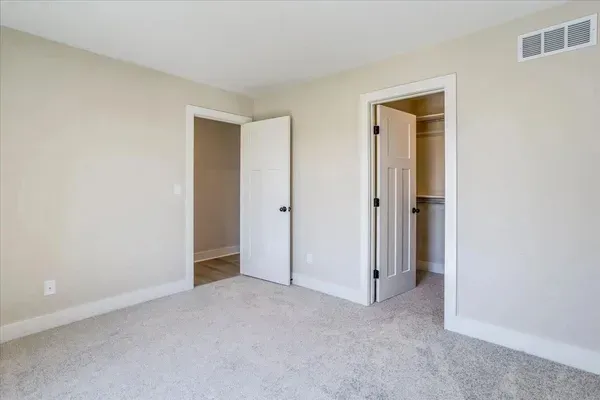 An empty bedroom with two doors and a closet.