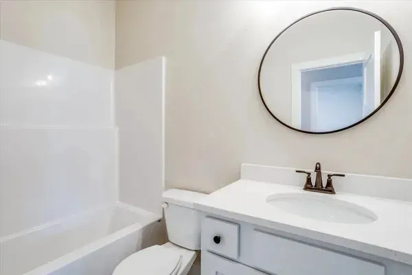 A bathroom with a toilet , sink , bathtub and mirror.