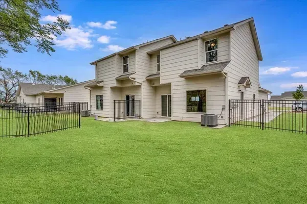 The backyard of a house with a fence and a lot of grass.