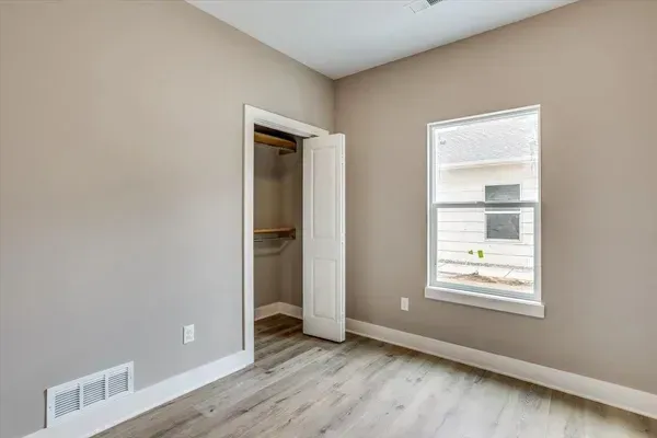 An empty room with a window and a closet.