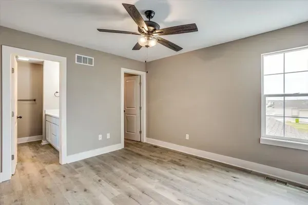 An empty bedroom with a ceiling fan and a window.