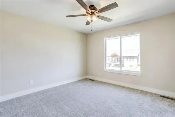An empty bedroom with a ceiling fan and a window.