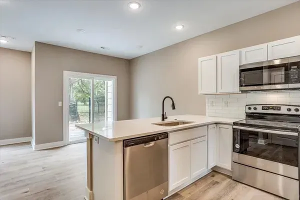 A kitchen with stainless steel appliances and white cabinets.