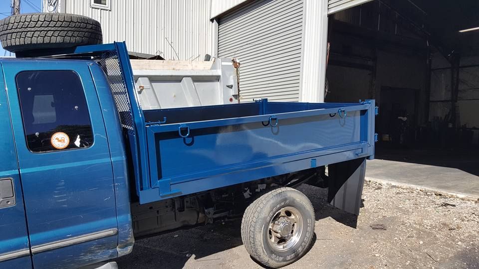 A blue dump truck is parked in front of a building.