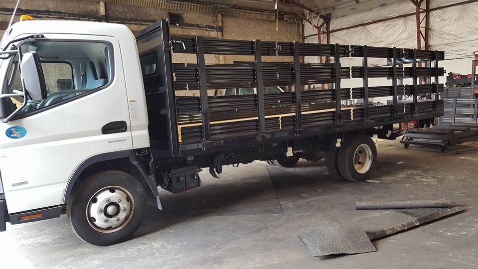 A white truck with a wooden bed is parked in a warehouse.