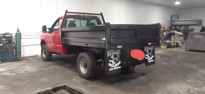 A red dump truck is parked in a garage.