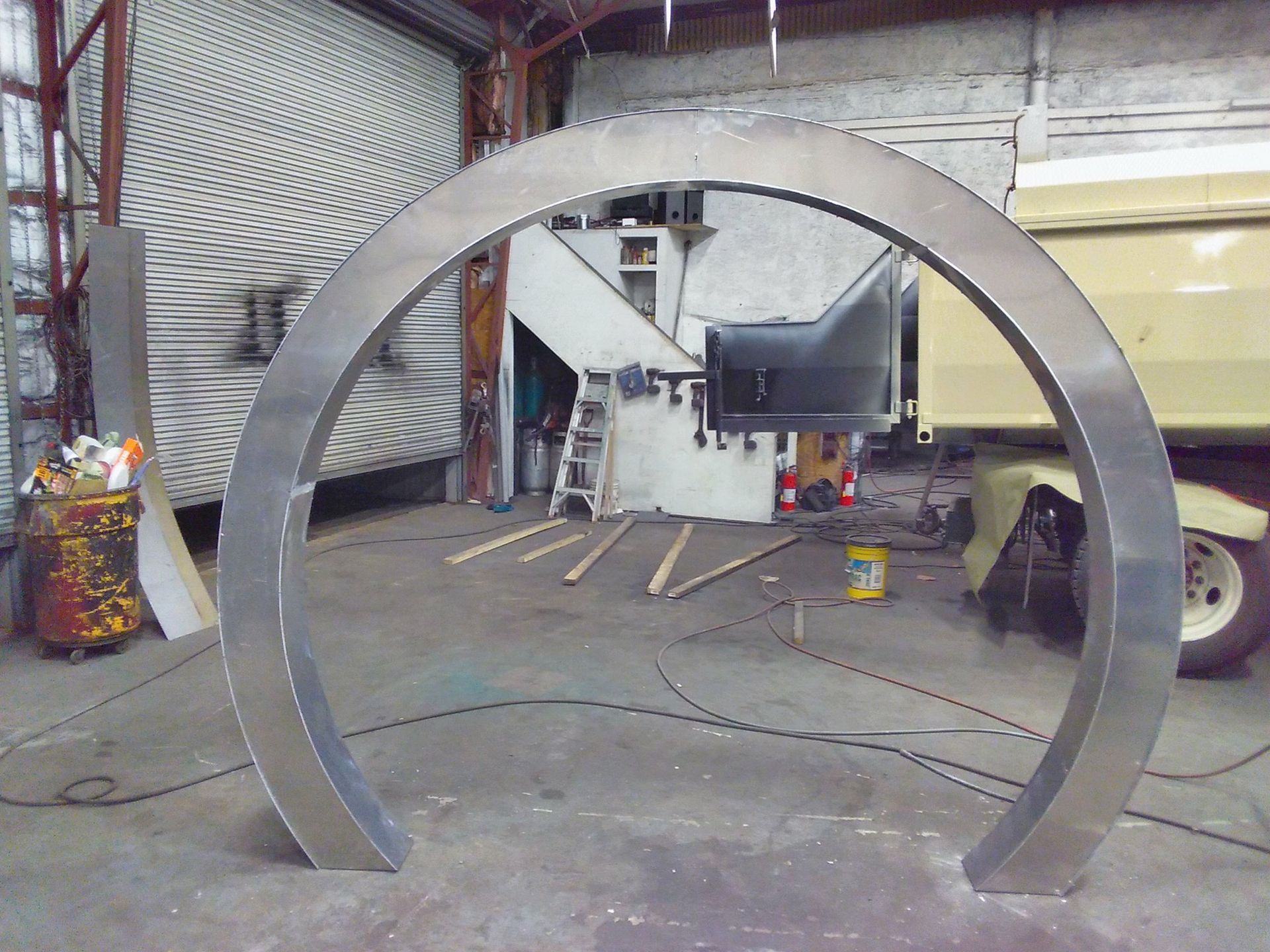 A large metal circle in a garage with a yellow truck in the background