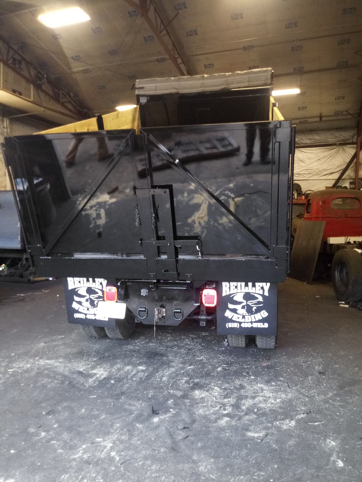 A black dump truck is parked in a garage.