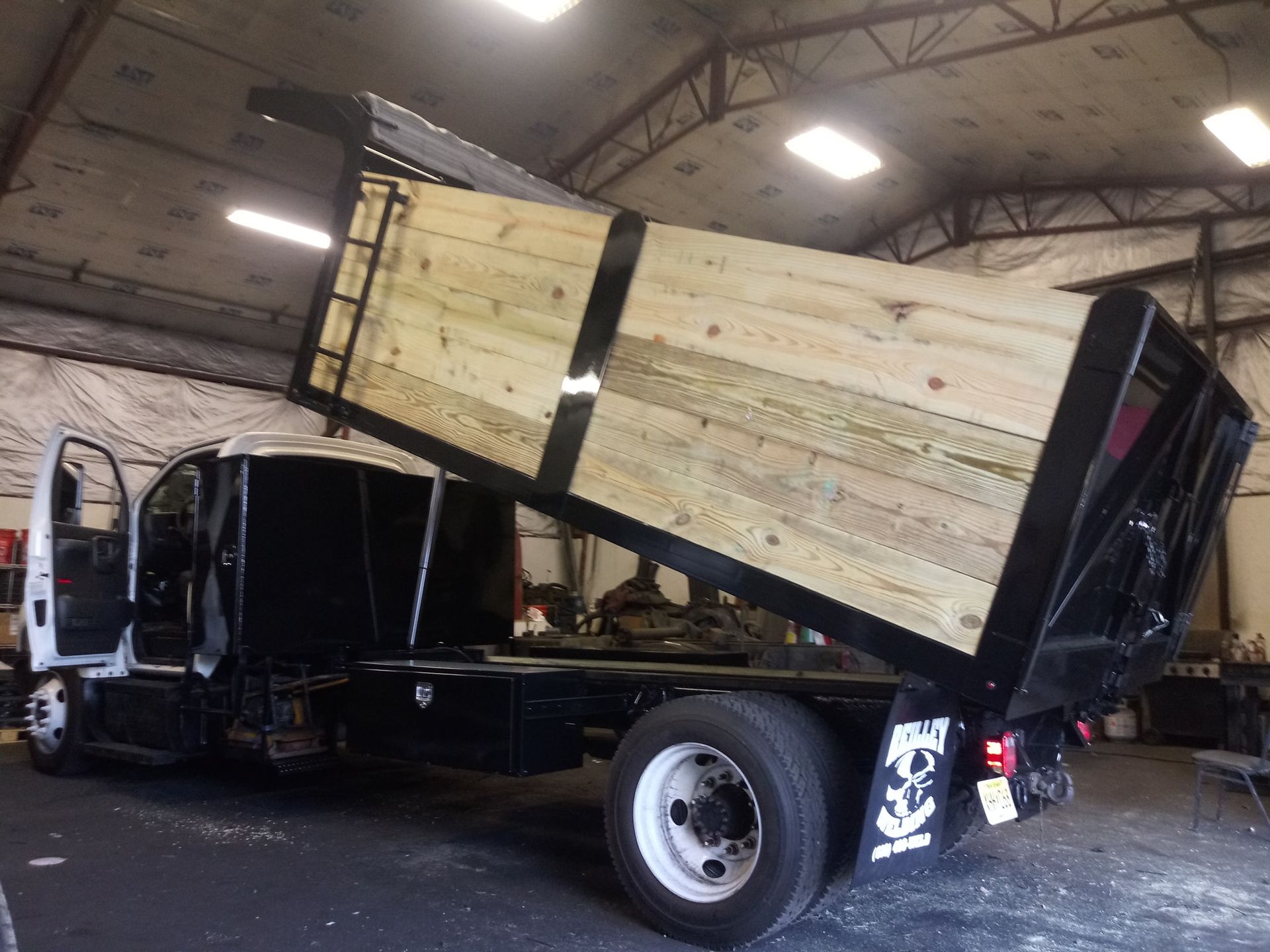 A dump truck with a wooden bed is parked in a garage