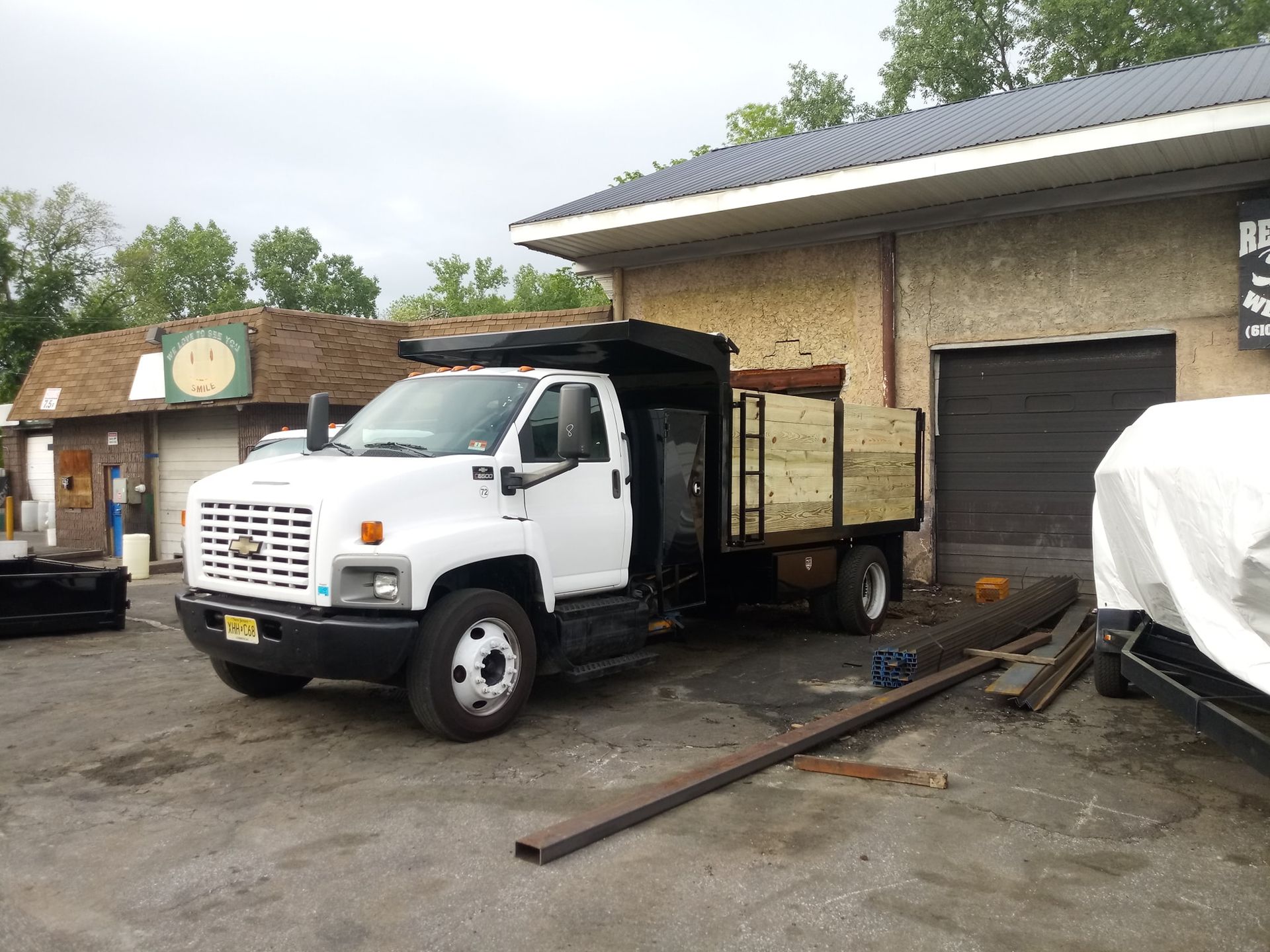 A white dump truck is parked in front of a building.