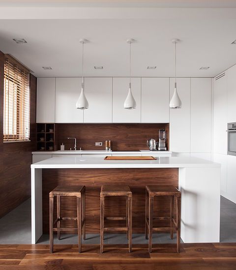 Modern kitchen with white cabinets, wooden accents, island with stools, and pendant lights.
