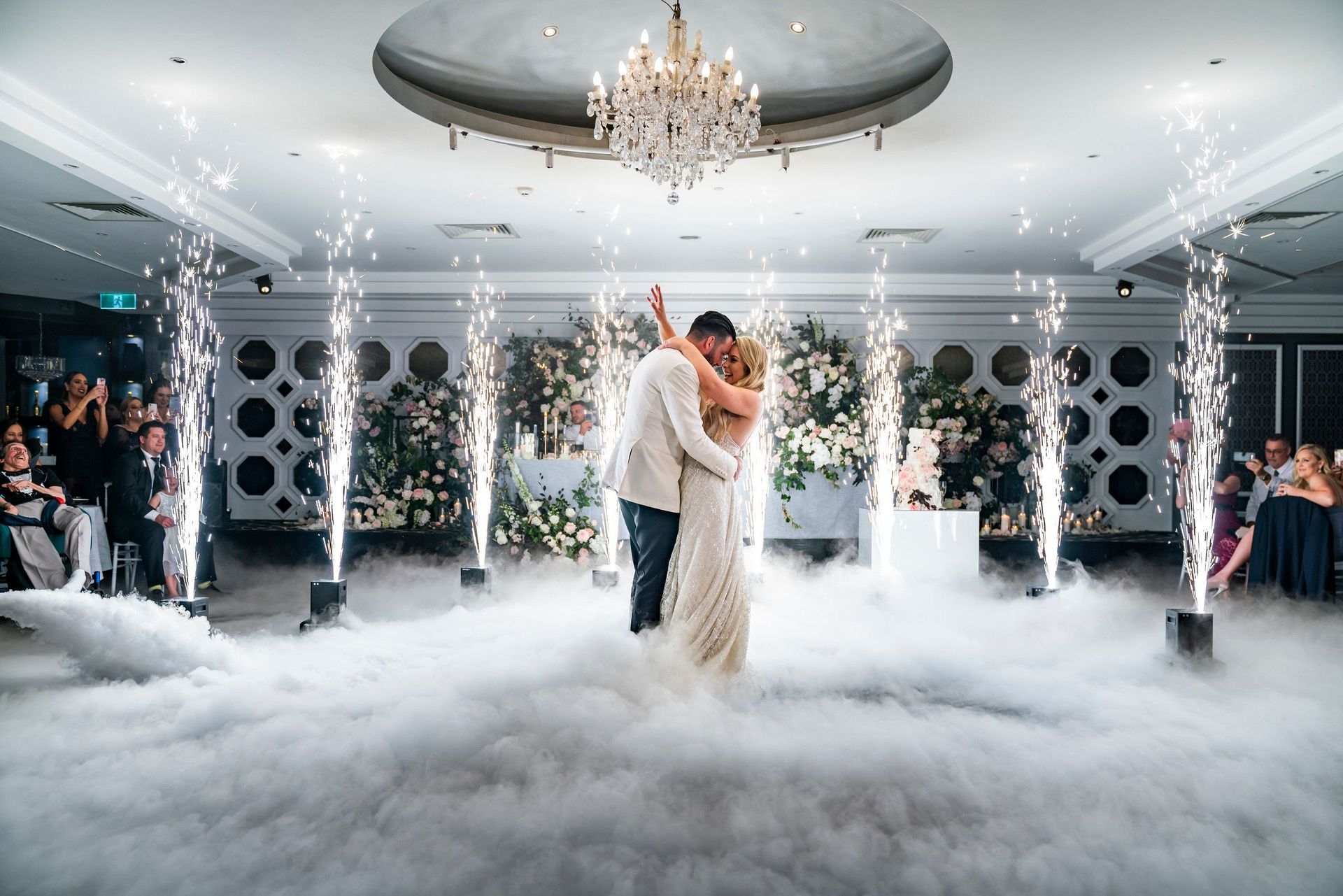 A bride and groom are dancing in the fog at their wedding reception.