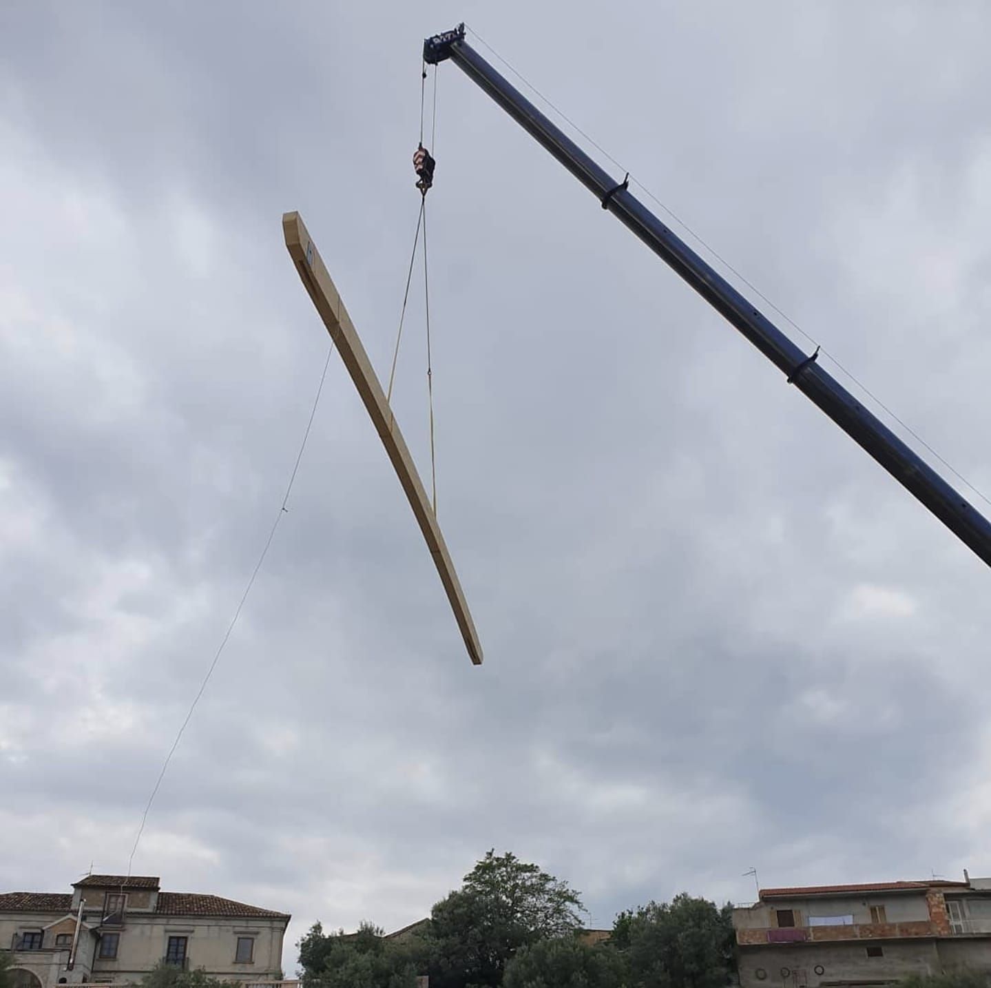 Una gru solleva un pezzo di legno in aria