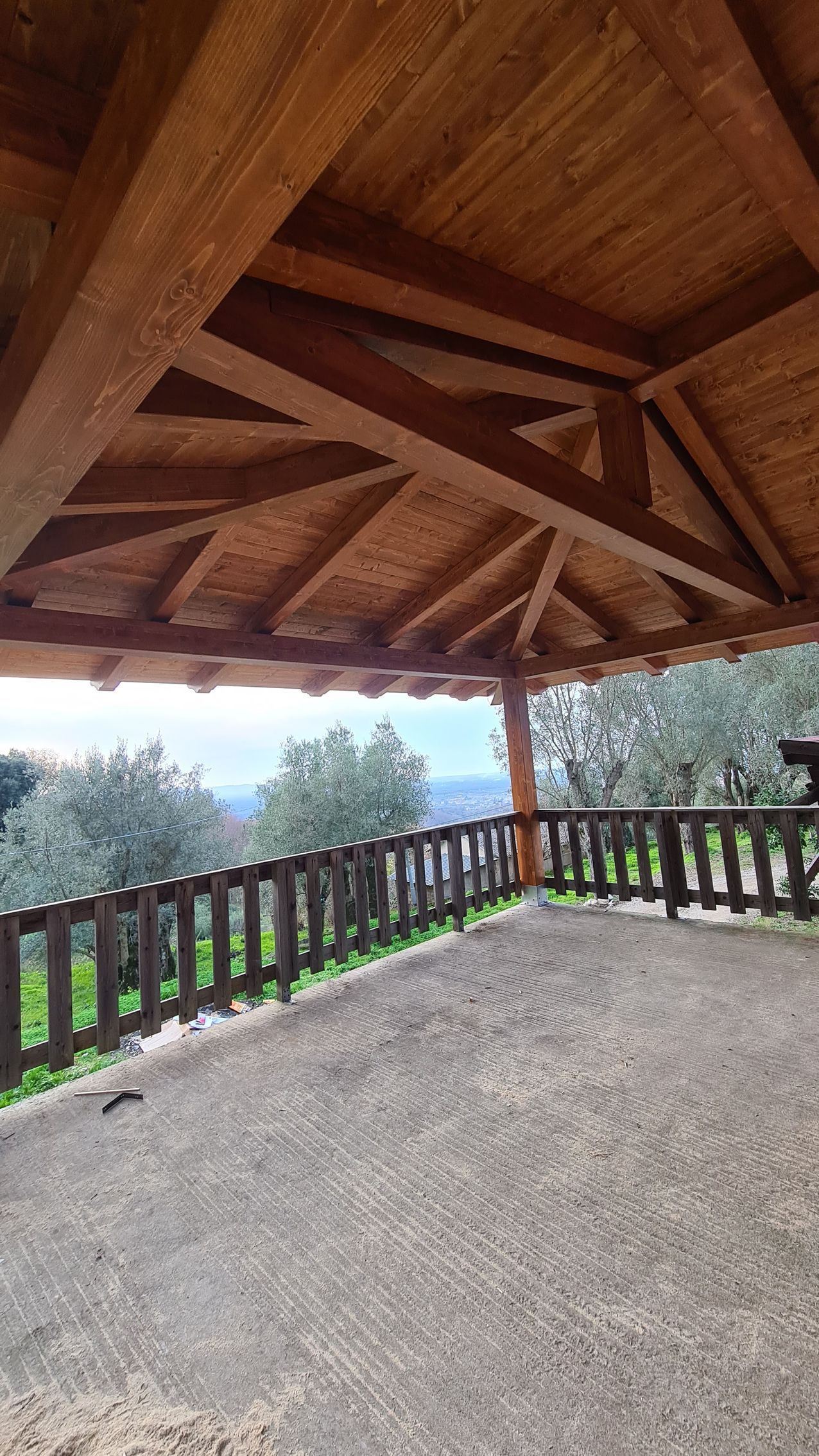 Gazebo in legno con recinzione e vista sulle montagne.