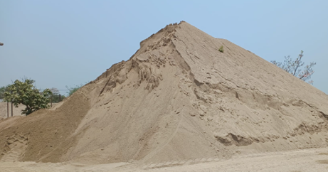 Hay un gran montón de arena encima de un campo de tierra.