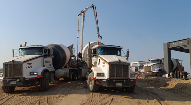 Dos camiones están estacionados uno al lado del otro en un camino de tierra.