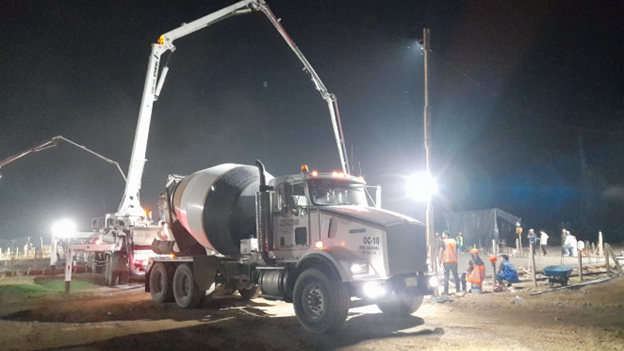 Un camión hormigonera está estacionado en un sitio de construcción por la noche.