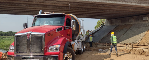 Un camión rojo pasa por debajo de un puente.