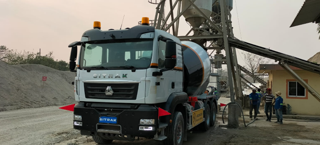 Un camión hormigonera está estacionado frente a una planta de hormigón.