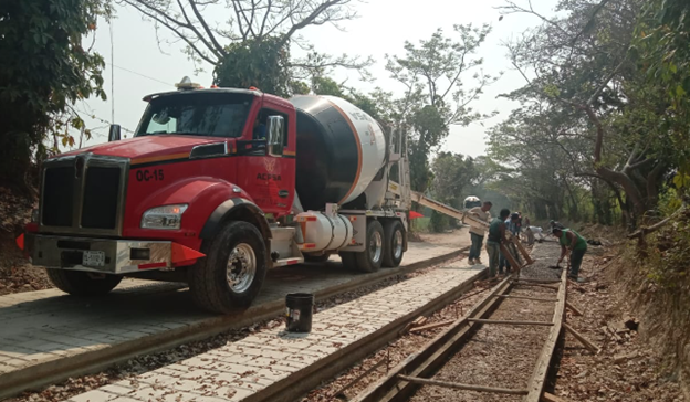 Un camión de cemento rojo circula por las vías del tren.