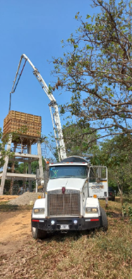 Un camión con una grúa conectada circula por un camino de tierra.
