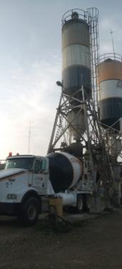 Un camión hormigonera está estacionado frente a un silo de hormigón.
