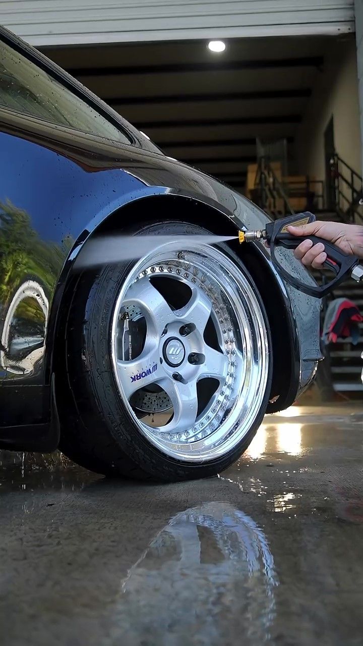 Auto detailer hand-washing a foam-covered Porsche 911 as part of a full exterior detail and paint correction prep at an Orlando detailing shop.