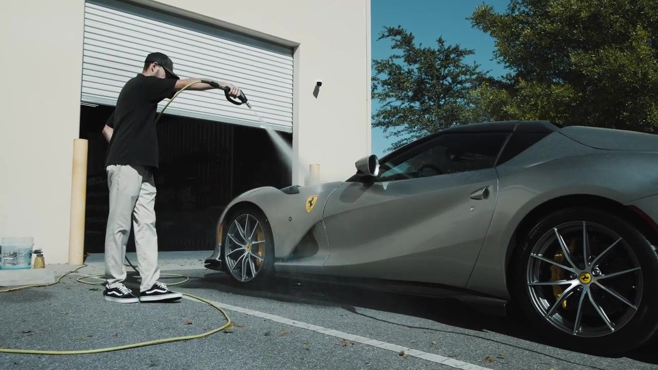 Detailer rinsing ceramic coated Ferrari 812 with high-pressure water in Florida