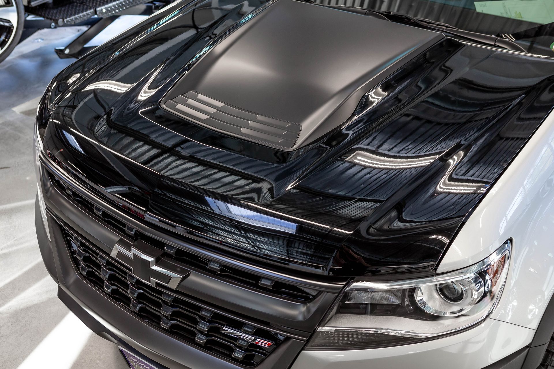 Black-and-silver pickup truck with a custom hood and chrome grille in a showroom