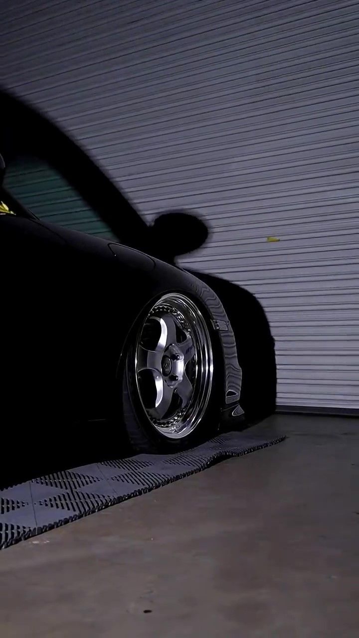 Inspecting the paint on a black Porsche 911 after having a multi-step paint correction.