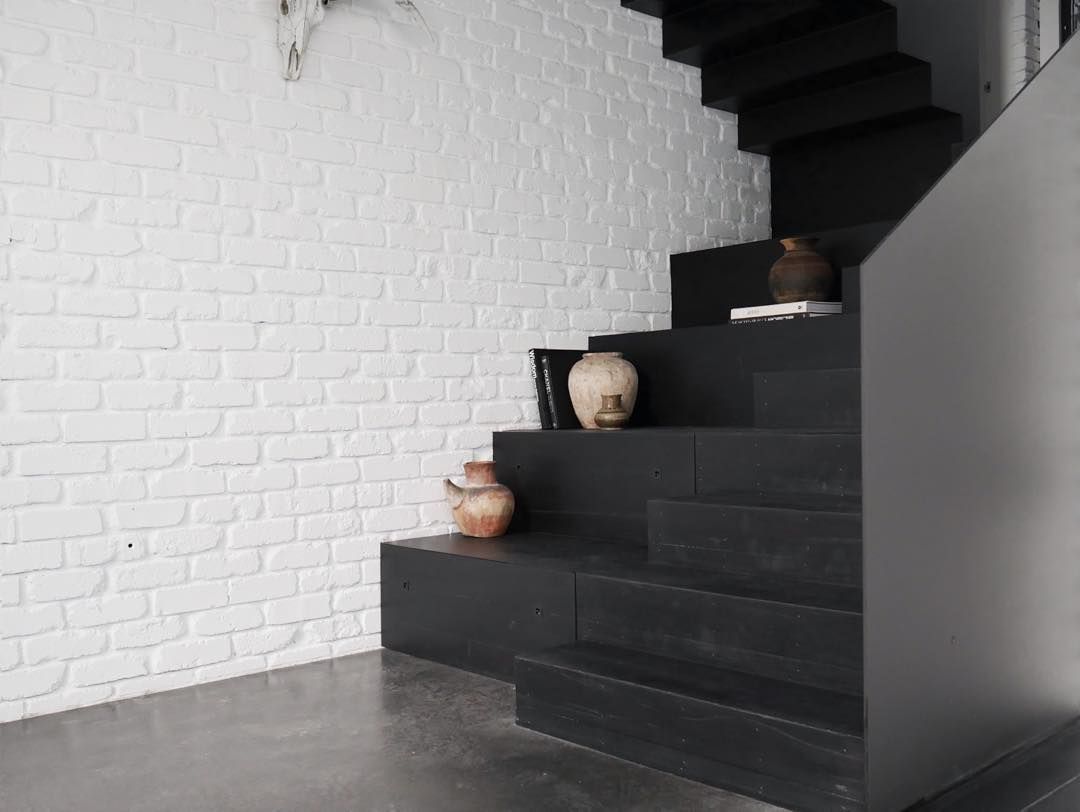 A black staircase with a white brick wall behind it