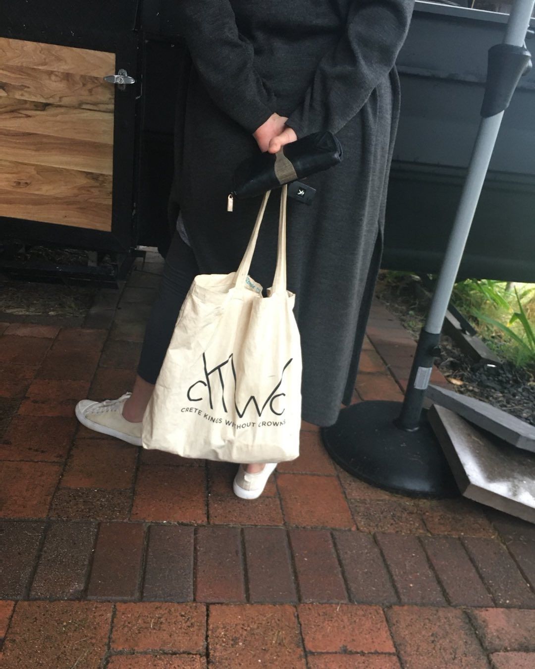 A woman is holding a tote bag that says chive on it