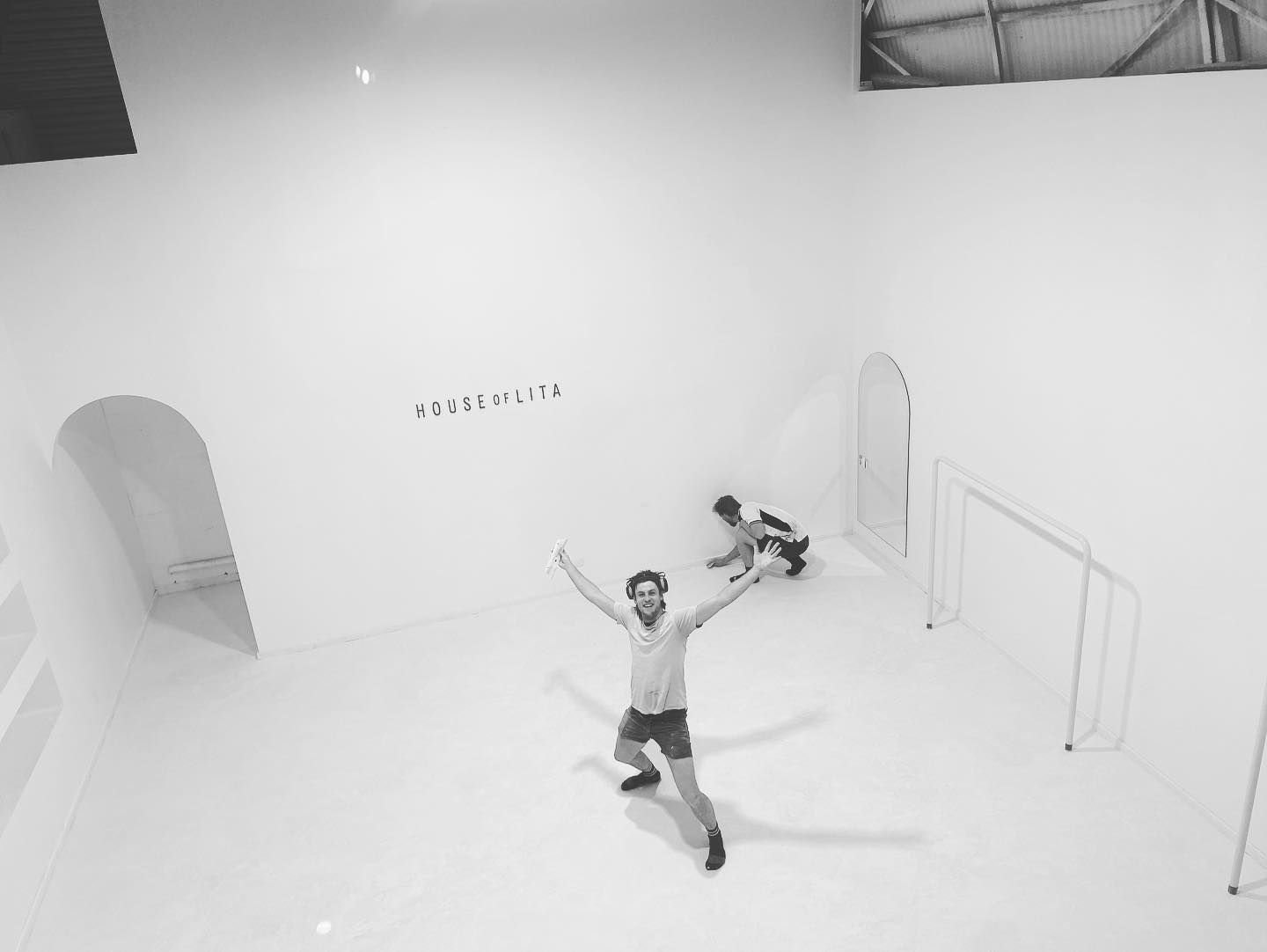 A man is standing in a white room with his arms outstretched.