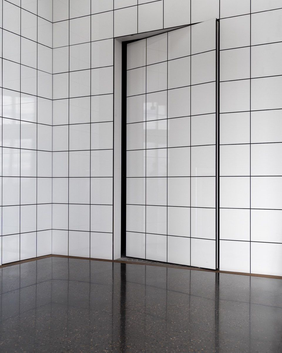 An empty room with white tiles and a black floor