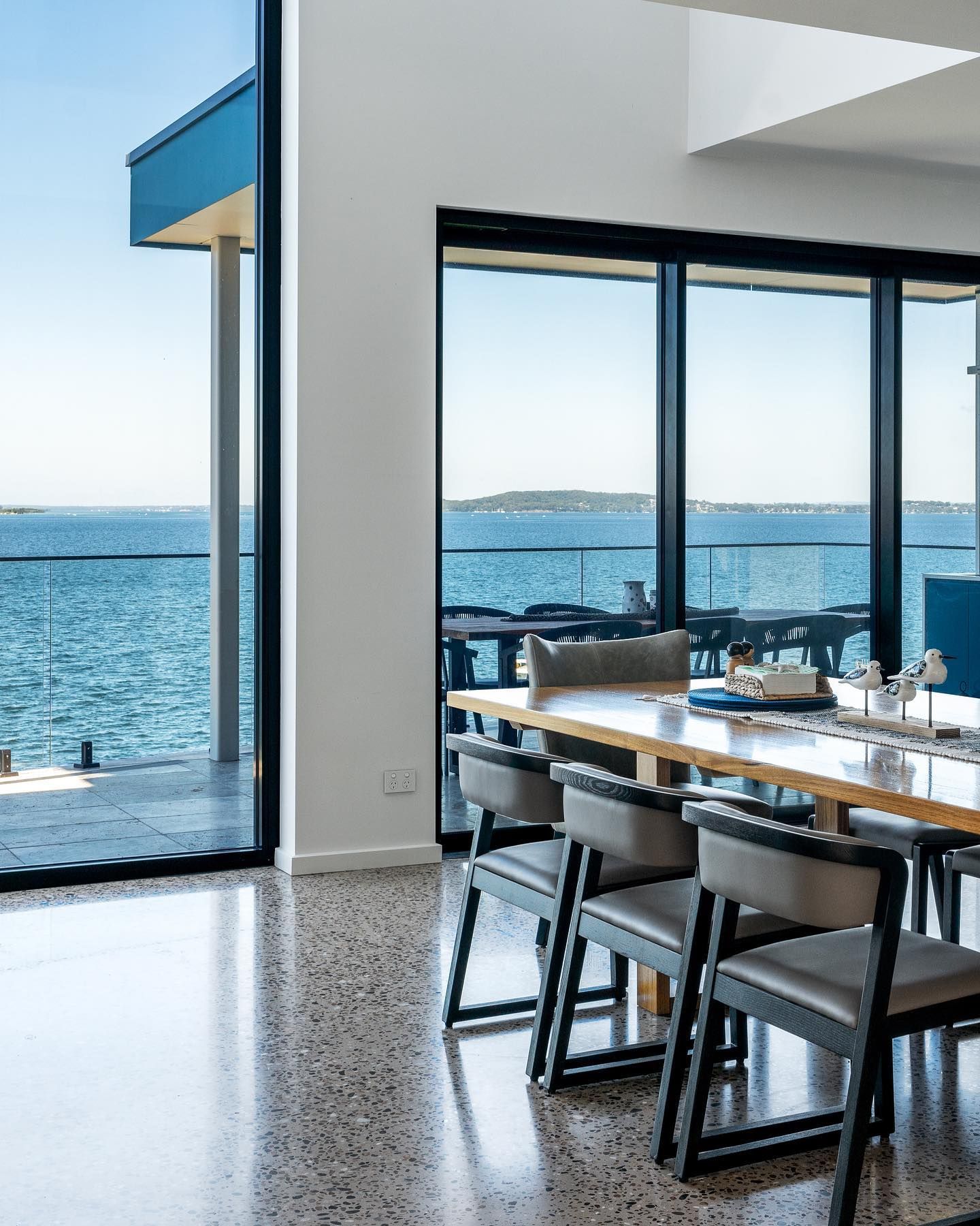 A dining room with a table and chairs and a view of the ocean.