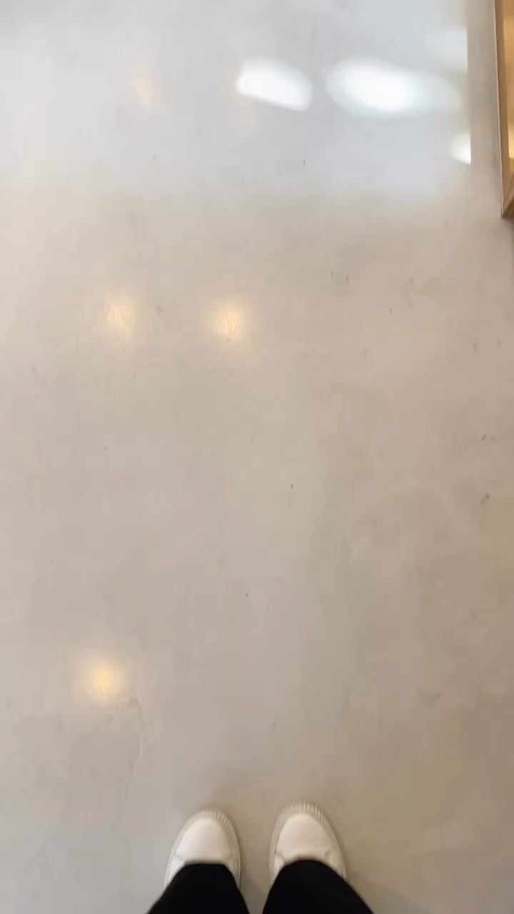 A person 's feet are standing on a white tiled floor.