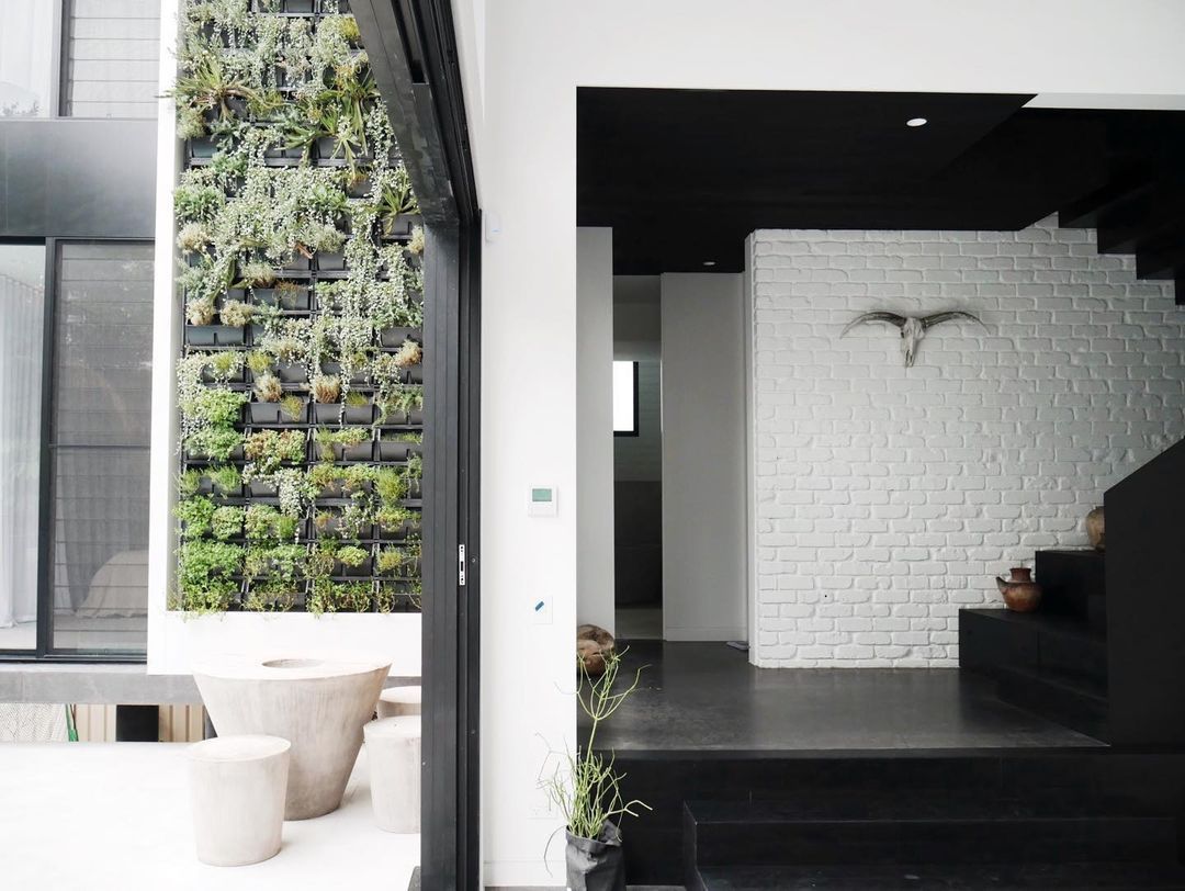 A living room with a staircase and a wall of plants